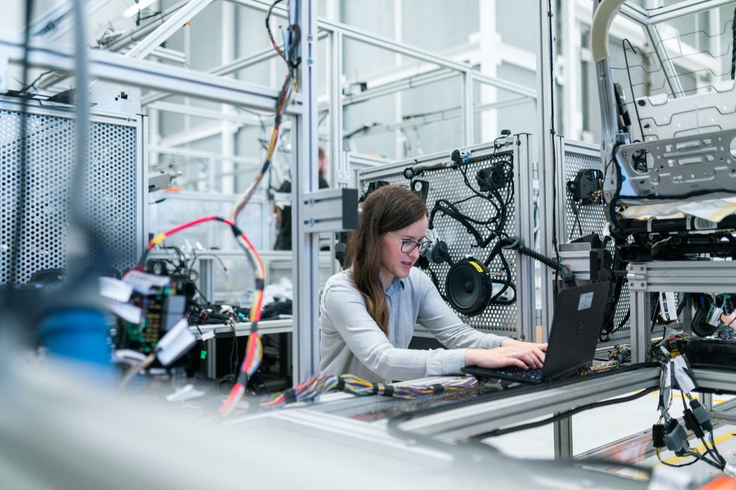 An engineer working on a laptop inside a vehicle wiring and seat test rig